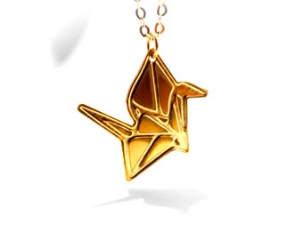 Könnte beinhalten: Eine goldene Halskette mit einem Origami-Kranich-Anhänger. Der Kranich ist ein Symbol für Frieden und Glück.