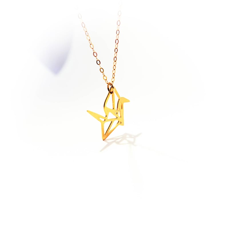 May include: A gold origami crane pendant necklace. The crane is a symbol of peace and good luck.