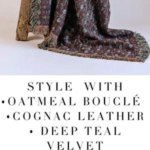 May include: A woven blanket with a floral pattern in shades of burgundy, teal, and cream. The blanket has a fringed edge and is draped over a wooden bench. The text on the image reads "HERITAGE COASTAL OR MOUNTAIN RETREAT WOVEN BLANKET."