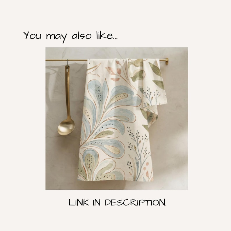 May include: A rectangular kitchen towel featuring a light cream background with a repeating pattern of large, stylised blue and green floral shapes, delicate stems, and small leaves. The towel hangs from a thin gold-toned metal rod.