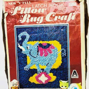 May include: Vintage "Sew 'N Tell" Pillow Rug Craft kit. The box features a latch hook design with an elephant on a blue background, with yellow and pink accents. The text reads "Pillow Rug Craft". Includes small figurines.