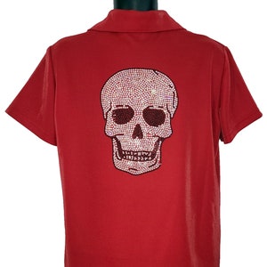May include: Red short-sleeved polo shirt with a large rhinestone skull design on the back.