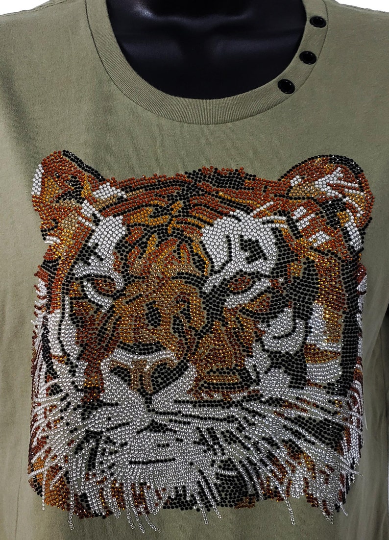 May include: A green t-shirt with a tiger face design made of rhinestones. The tiger's face is made of black, brown, and silver rhinestones.