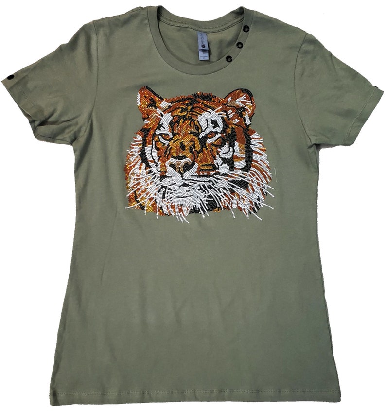 May include: A green t-shirt with a beaded tiger face design. The tiger's face is made of orange, brown, white, and black beads.