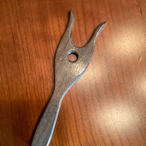 May include: A wooden tool with a forked end and a hole in the center. The tool is gray and has a smooth finish.