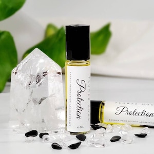 May include: Two 10 ml roller bottles with black caps and white labels. The labels read "Flower Moon Protection Energy Protection Aromatherapy".