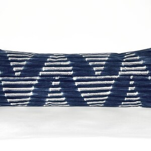 May include: A long, rectangular blue and white patterned throw pillow. The pillow has a white background with a blue geometric pattern.
