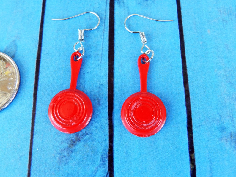 K&ouml;nnte beinhalten: Ein Paar rote Mini-Bratpfannen-Ohrringe mit silbernen Haken.