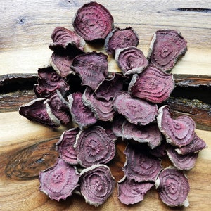 Peut inclure: Un tas de chips de betterave séchées sur une surface en bois. Les chips sont d'une couleur rouge violacé foncé et ont une texture légèrement ridée.