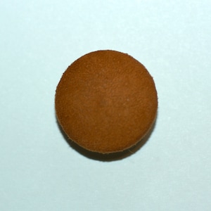 Puede incluir: Un botón redondo de gamuza marrón.