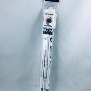 May include: A package of three white pencils with black and white dog-themed designs. The pencils are labeled with "THE DOG" and the website address. The packaging includes a small image of a dog's face.
