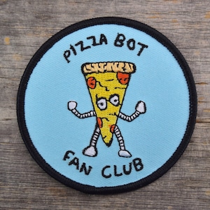 May include: A blue and black circular patch with the text "Pizza Bot Fan Club" and a cartoon pizza slice with eyes and arms.
