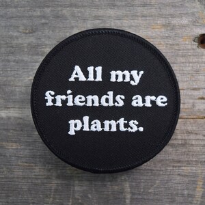 May include: A black round patch with white embroidery that reads "All my friends are plants."