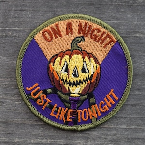 May include: A green, purple, and orange embroidered patch with a jack-o'-lantern and the text "On a night just like tonight".