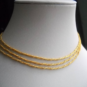 May include: A gold chain necklace with three strands of twisted rope chain.