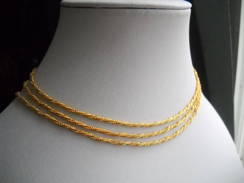 May include: A gold chain necklace with three strands of twisted rope chain.