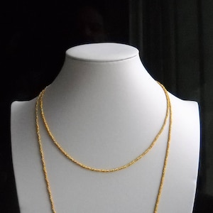 May include: A gold chain necklace with a twisted rope design. The necklace is displayed on a white mannequin bust.