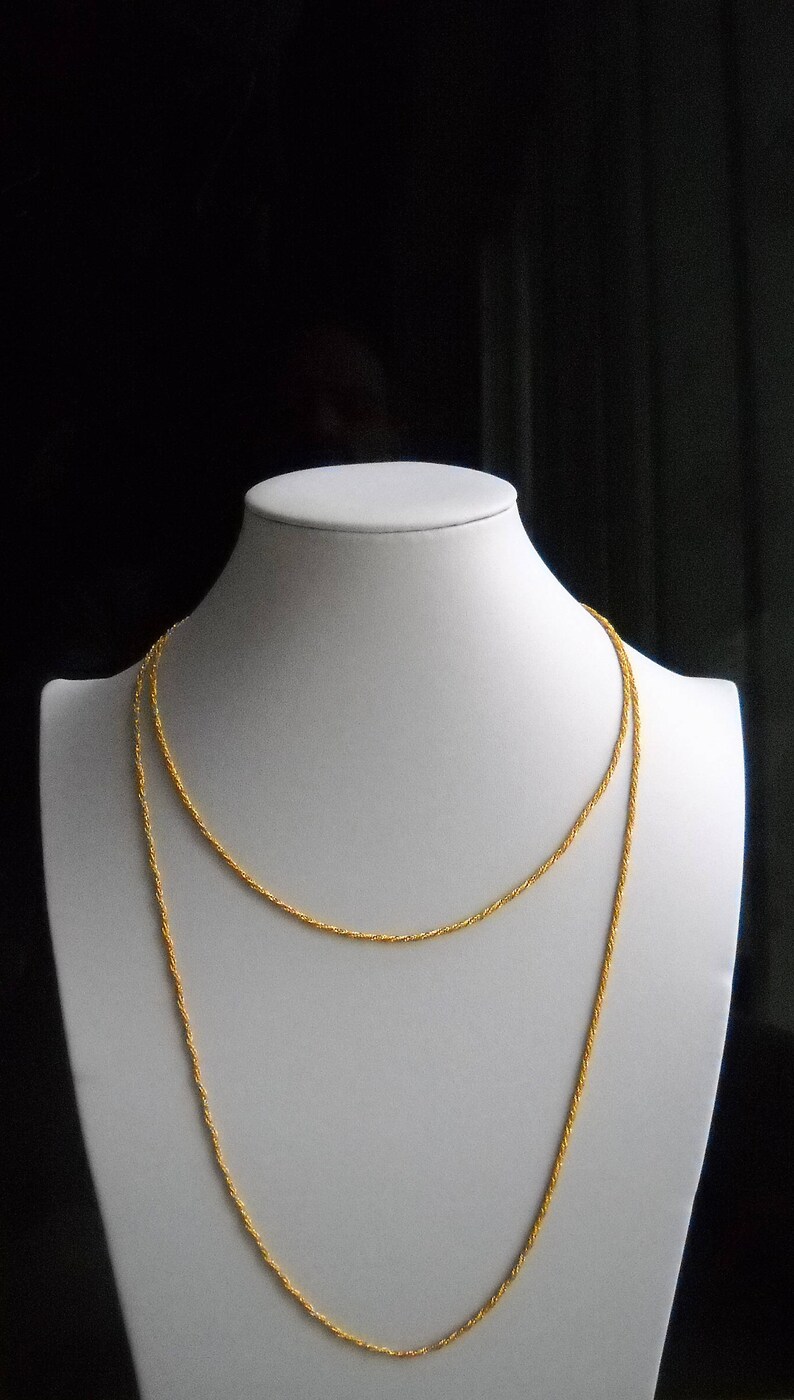 May include: A gold chain necklace with a twisted rope design. The necklace is displayed on a white mannequin bust.