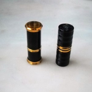 Two 50 French petrol lighters, cylindrical in shape, gold-plated brass; &quot;Collection Rue de La Paix&quot; inscription on the bottom. Working