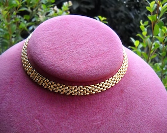 May include: A gold chain necklace with a box link design. The necklace is displayed on a pink velvet stand.