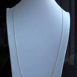 Può includere: Una collana a catena d'argento su un manichino bianco. La catena è sottile e delicata, e misura circa 50 cm di lunghezza.