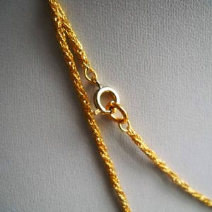 May include: A gold chain necklace with a lobster clasp closure. The chain is made of two strands of twisted rope.