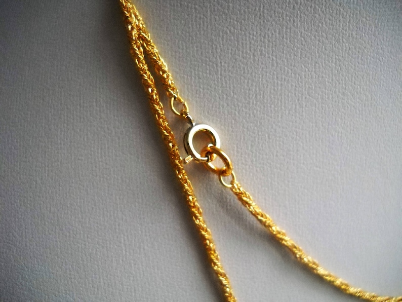 May include: A gold chain necklace with a lobster clasp closure. The chain is made of two strands of twisted rope.
