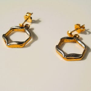 Sechseckige französische Ohrstecker aus den frühen 80er Jahren, vergoldeter Messingrahmen, der an der oberen und unteren Spitze durch zwei stahlplattierte Messingstücke verstärkt ist.