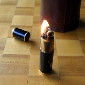 Funktionierendes französisches Benzinfeuerzeug aus den 1940er Jahren, zylindrisch geformt, mit Brettspielmotiven „Pokerwürfeln“, vergoldetes Messing oben und unten