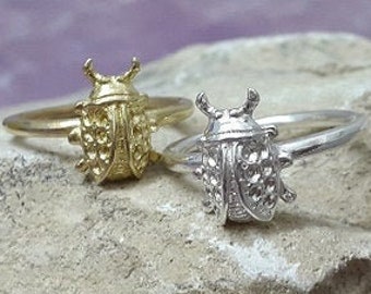 May include: Two silver rings with a beetle design. One ring is gold and the other is silver.