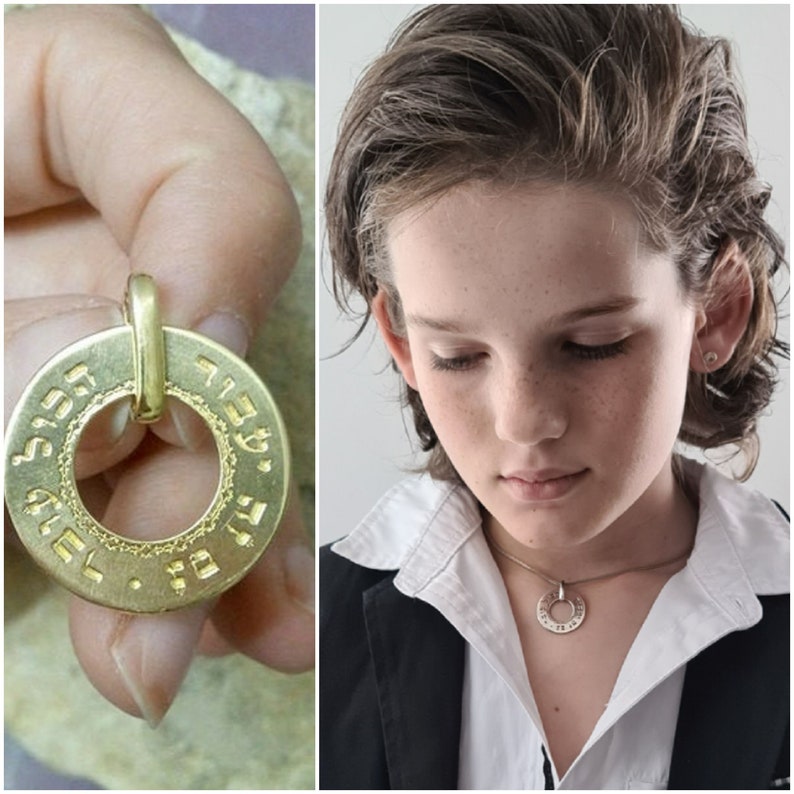 Puede incluir: Un collar con un colgante redondo de oro grabado con texto hebreo. El colgante tiene un peque&ntilde;o bucle en la parte superior para sujetarlo a una cadena.
