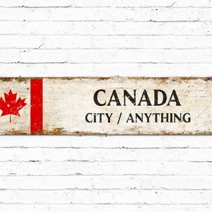 Peut inclure: Panneau métallique rectangulaire vieilli avec le drapeau canadien à gauche et le mot « CANADA » en noir gras. En dessous, il est écrit « CITY / ANYTHING ».
