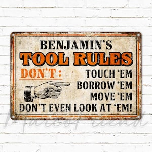 May include: A vintage-style metal sign with a distressed, rusty look. It reads "Benjamin's Tool Rules: Don't: Touch 'em, Borrow 'em, Move 'em, Don't even look at 'em!"