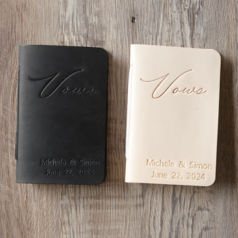 Peut inclure: Deux livres de v&oelig;ux en cuir, l'un noir et l'autre cr&egrave;me, avec le mot "V&oelig;ux" en relief sur la couverture. Les livres sont personnalis&eacute;s avec les noms "Michele & Simon" et la date "22 juin 2024".