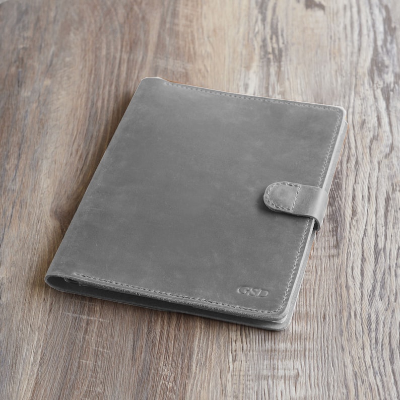 May include: A gray leather notebook with a flap closure and a small metal logo that says "GSD".