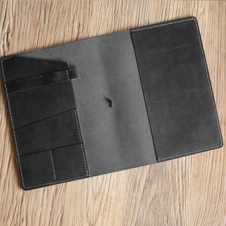 May include: A black leather notebook with a flap closure and multiple pockets on the inside cover.