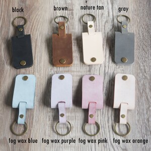 May include: Ten leather keychains in various colors, including black, brown, tan, gray, blue, purple, pink, and orange. The keychains are arranged in two rows of five. Each keychain has a metal ring and a leather strap.