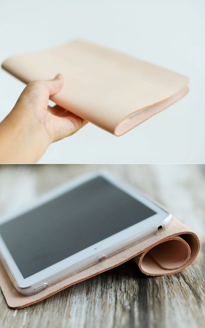 May include: A light brown leather tablet case with a white tablet inside. The case is rolled up and the tablet is visible on the top of the roll.