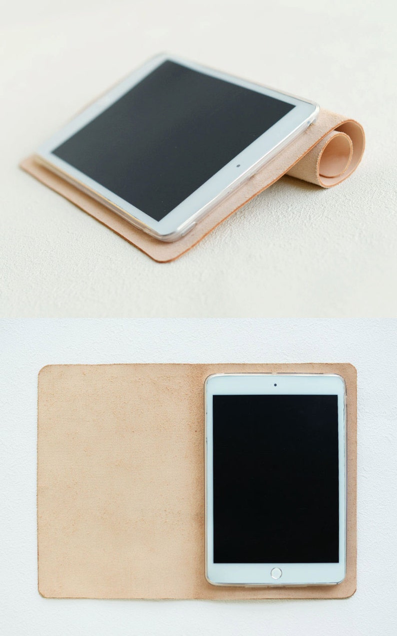 May include: A light brown leather case for a tablet. The case is folded in half and the tablet is inside. The tablet has a black screen and a white frame.