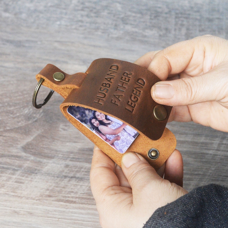 May include: Brown leather keychain with a photo insert and the words "Husband Father Legend" embossed on the front.