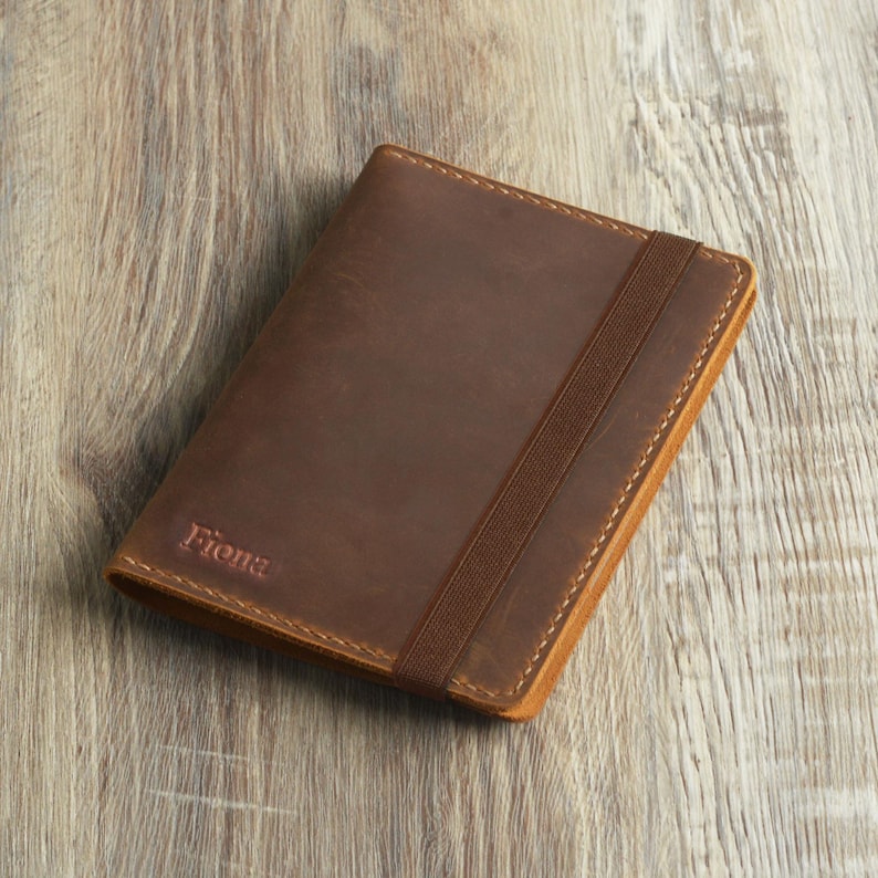 Peut inclure: Une couverture de carnet en cuir marron avec une fermeture &eacute;lastique et le nom "Fiona" grav&eacute; sur le devant.