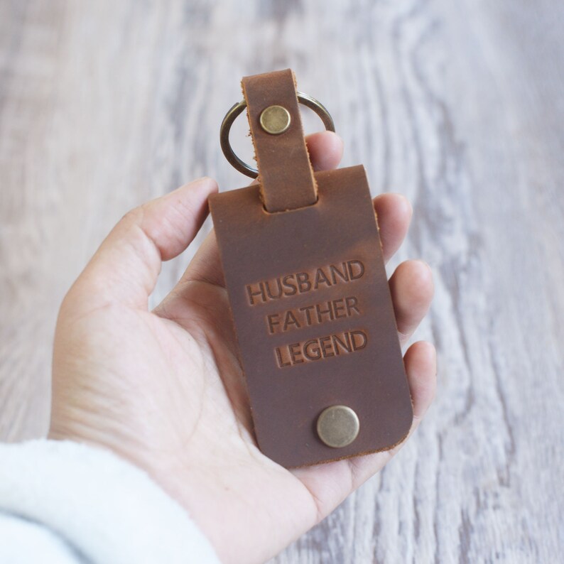 May include: Brown leather keychain with a metal ring and the text "Husband Father Legend" embossed on the front.