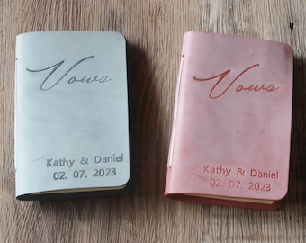 May include: Two leather-bound journals with the word "Vows" embossed on the front cover. The journals are in gray and red and have the names "Kathy & Daniel" and the date "02. 07. 2023" embossed on the bottom.