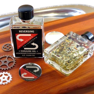 May include: Two clear glass bottles with black caps containing a dark liquid. The bottles are labeled "REVERSING" and have a red arrow symbol. The bottles are on a wooden surface with a silver tray and metal gears.