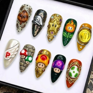 May include: A set of ten long, almond-shaped acrylic nails, each featuring a different design inspired by the Super Mario video game series. Designs include a leaf, a hat, a star, a fire flower, a coin, a wing, mushrooms, and more.