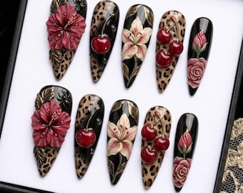 May include: A collection of ten long, pointed artificial nails. Each nail showcases a distinct design, such as leopard print, cherries, lilies, and roses. The nails are decorated with 3D floral and fruit embellishments, creating a striking and artistic appearance.
