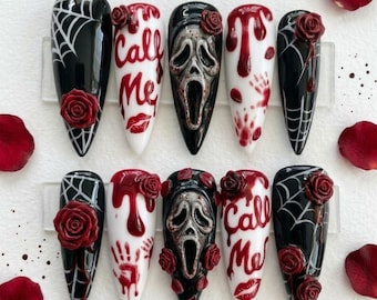 May include: A set of ten stiletto-shaped press-on nails featuring a horror theme. Designs include black nails with white spiderwebs and red roses, white nails with red blood drips, handprints, red roses, and the text Call Me with a red lip print.