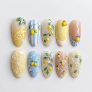 May include: A set of ten press-on nails featuring various lemon-themed designs. The nails display patterns including yellow lemon slices, blue and white stripes with lemons, green leafy branches with yellow lemons, white polka dots, and small white flowers.
