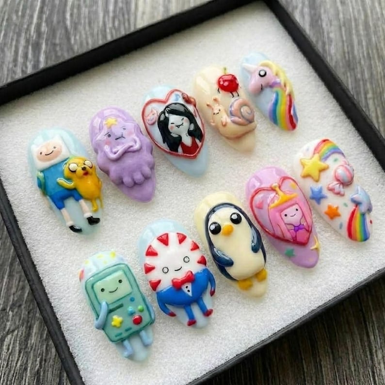 Puede incluir: Un conjunto de diez dise&ntilde;os de u&ntilde;as personalizados, cada uno con un personaje diferente de la serie animada Adventure Time. Las u&ntilde;as est&aacute;n pintadas en varios colores y presentan elementos 3D, incluyendo a Finn, Jake y la Princesa Chicle.