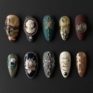 May include: Ten artificial nails with detailed designs. Each nail showcases unique artwork, such as a cameo, a clock, a fox, and abstract patterns. The colour palette includes brown, teal, and cream, with metallic accents.